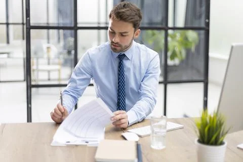Young man is working with papers while sitting in the office. Stock Photos