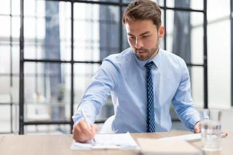 Young man is working with papers while sitting in the office. Successful en.. Foto stock