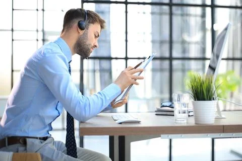 Young man is working with papers while sitting in the office. Successful en.. Stock Photos
