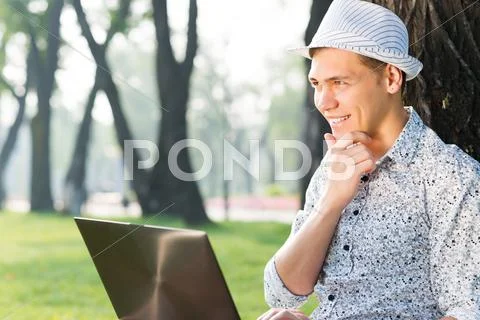 Young man working in the park with a laptop Stock Photos