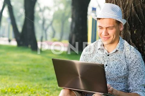 Young man working in the park with a laptop Stock Photos