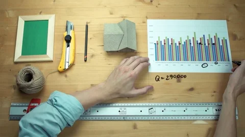 Young man working with printed graphs making notes with marker at wooden desk Stock Footage 82902205