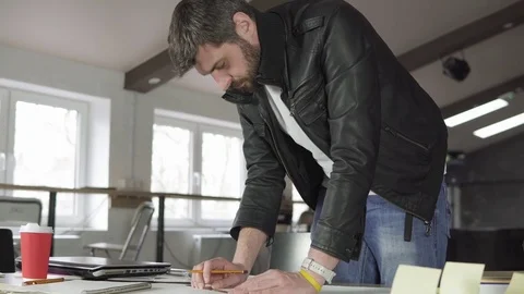 Young man working on a project, drawing and thinking in modern office. Coffee Stock Footage
