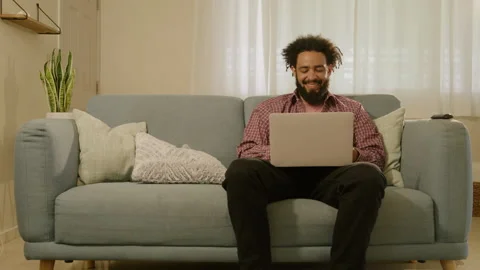A Young Man Working Remotely on His Laptop from the Comfort of His Home Vídeos de archivo 285295387