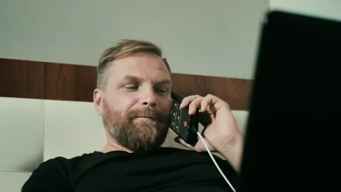 Young man working remotely, using a laptop at home, talking on the phone Stock Footage 274165180