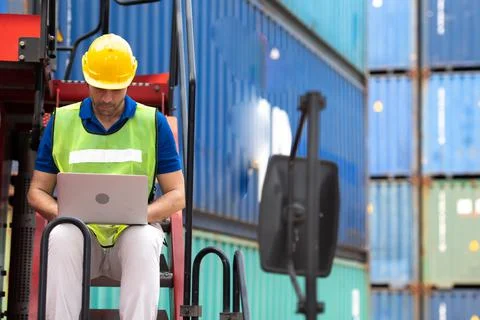 Young man working sitting on crane truck with computer at logistic import and Stock Photos
