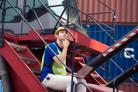 Young man working sitting on crane truck with computer at logistic import and Stock Photos