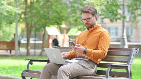 Young Man Working with Smartphone and Laptop Outdoor 動画素材 282428679