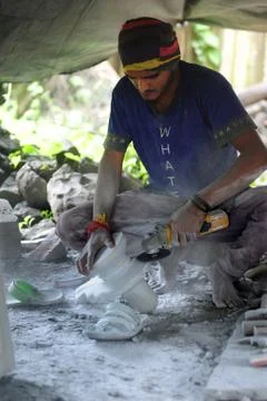 Young man working on a stone sculpture with a hand held motor grinder. Stock Photos