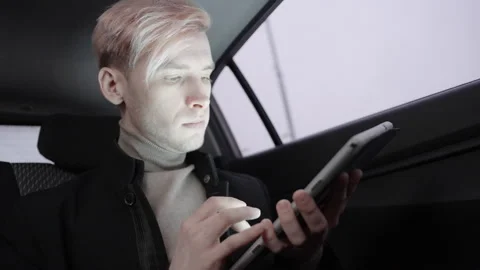 A young man working, studying or communicating with tablet in taxi. 库存影片 196099936