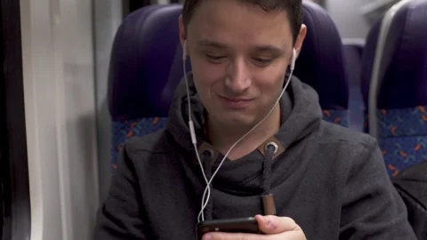 Young man working on a train and having fun with a smartphone and serving music Stock Footage 120466711