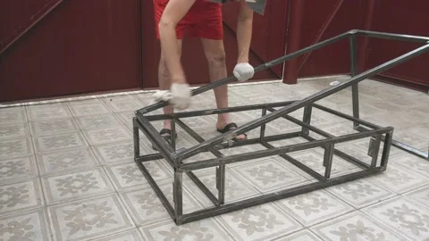 A young man in a working uniform and gloves thoroughly wipes a metal frame 库存影片 145394946