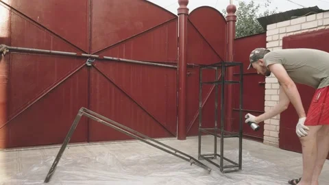 A young man in a working uniform paints a frame with a balloon with black paint Vidéo 145395328