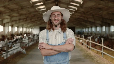 Young man in working uniform standing at farm with goats Stock Footage 157559042