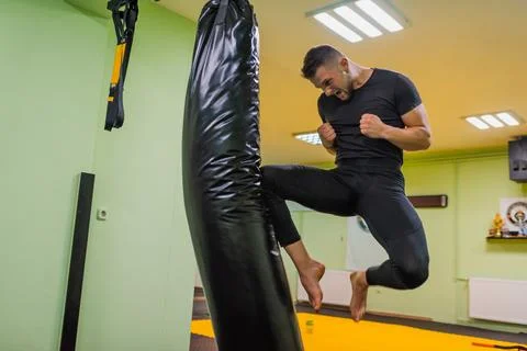 A young man workout or training a kick on the punching bag in gym male figh.. Stock Photos
