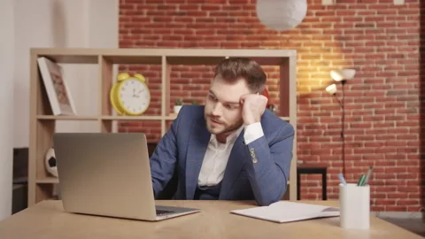 A young man at the workplace is typing on a laptop then getting upset. 動画素材 194363690