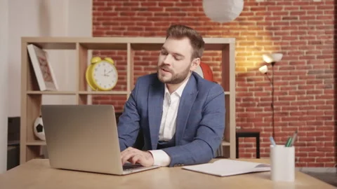 A young man at the workplace is typing on a laptop, then he gets very angry. Vidéo 194364868
