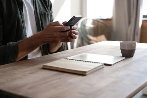 Young man at workplace using mobile phone, checking social media on smartphon Fotos de archivo