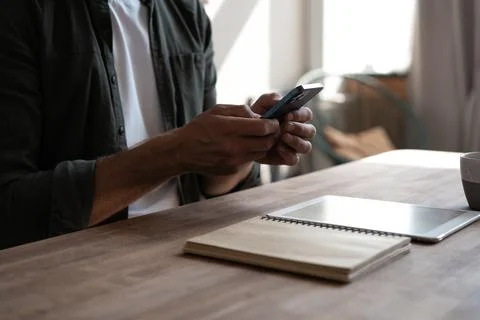 Young man at workplace using mobile phone, checking social media on smartphon Stock Photos
