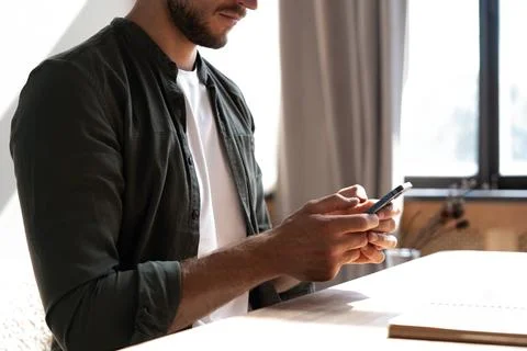 Young man at workplace using mobile phone, checking social media on smartphon Stock Photos