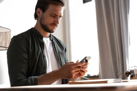 Young man at workplace using mobile phone, checking social media on smartphon 스톡 사진