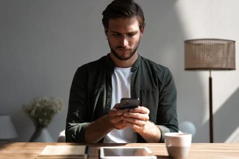 Young man at workplace using mobile phone, checking social media on smartphon Stock Photos