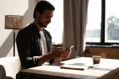 Young man at workplace using mobile phone, checking social media on smartphon Foto stock