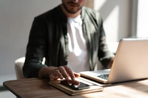 Young man at workplace using mobile phone, checking social media on smartphone Stock Photos