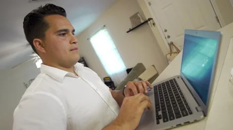 Young man works on computer as camera pushes in Stock-Footage 64339531