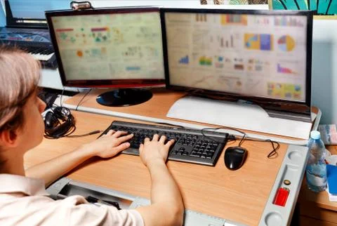 A young man works at a computer, sitting at a table in a room, distance learn Stock Photos