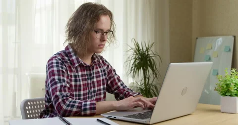 A young man works on a computer while sitting in the interior.  Stock Footage 198657985