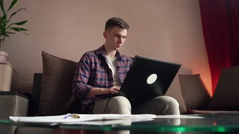 A young man works from home on a computer. quarantine, isolation. cozy room Stock Footage 212610717