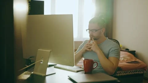 A young man works at home using a desktop computer, thinking about the task. Stock Footage 248004775