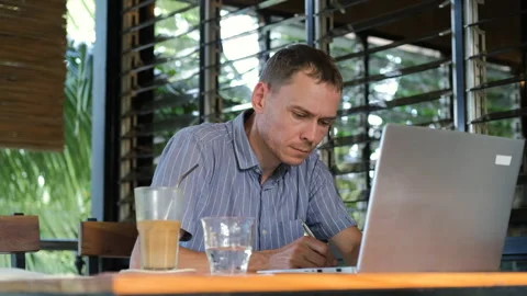 Young man works on laptop while enjoying coffee 스톡 동영상 312382600