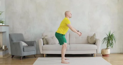 A young man works out doing squats at home. Side view. Stock Footage 152783228