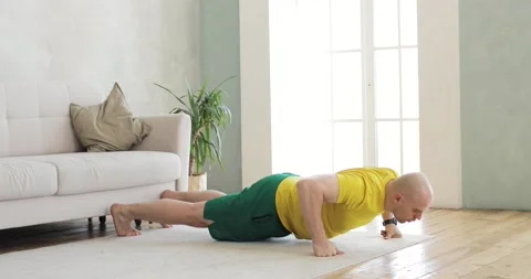 A young man works out doing push-ups on his fists at home. Side view. Stock Footage 152783703