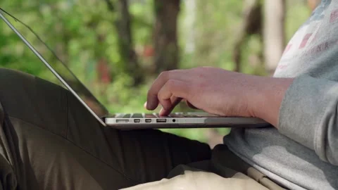 A young man works remotely at a computer in the fresh air. Stock Footage 241404936