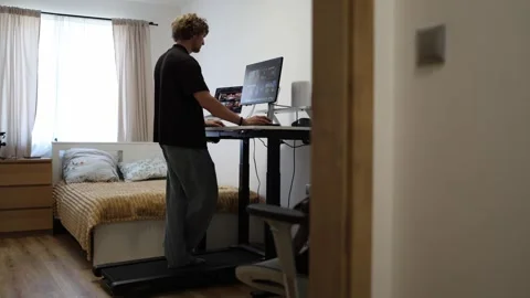 Young man works standing at an adjustable desk using two computer screens Stock Footage 346881809