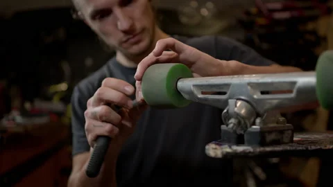 Young Man In The Workshop Attaches Wheel To Skateboard. Many Tools And Parts In Vidéo 152068959