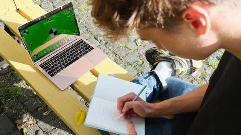 Young man writes outline having textbook on knee Stock Footage 262037322