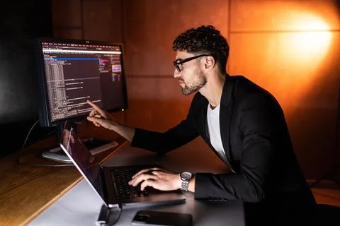 Young man writes program code on a computer, programmer work in home office. Photos