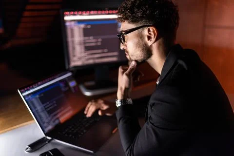 Young man writes program code on a computer, programmer work in home office. Stock Photos