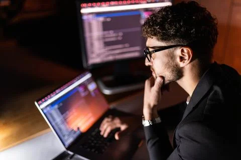 Young man writes program code on a computer, programmer work in home office. Stock Photos