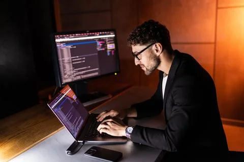 Young man writes program code on a computer, programmer work in home office. Photos