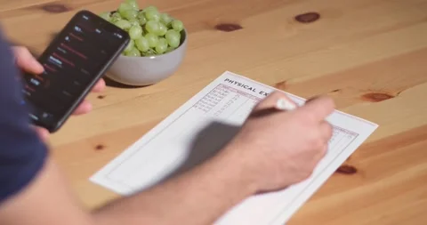 A young man writes weight, BMI, blood pressure, heart rate, and cholesterol Видео 160888366