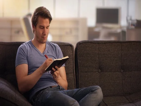Young man writing into his diary Stock Footage 78629445