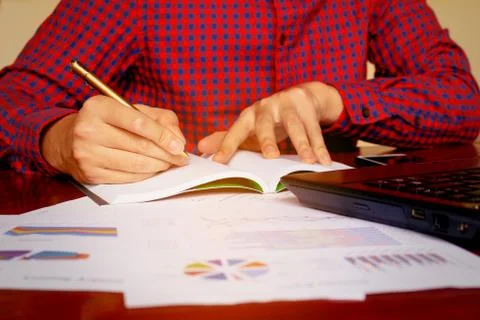 Young man writing make notes with calculate about cost at home office. Stock Photos