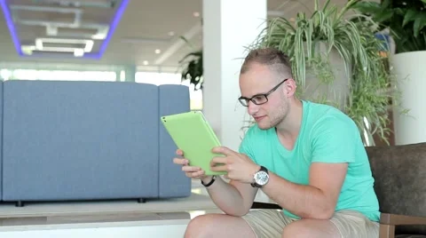 Young man writing a message on tablet from hotel lobby. Stock Footage 53490464