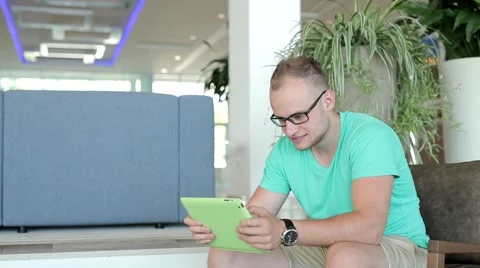 Young man writing a message on tablet from hotel lobby Stock Footage 53569361