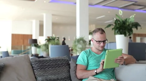 Young man writing a message on tablet from hotel lobby Stock-Footage 54543895